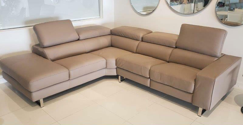 large Italian sectional in taupe with light walls and round mirrors behind it